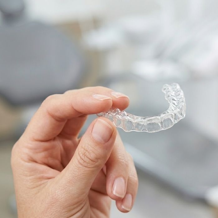 A clear Invisalign aligner being held up to show its transparency.